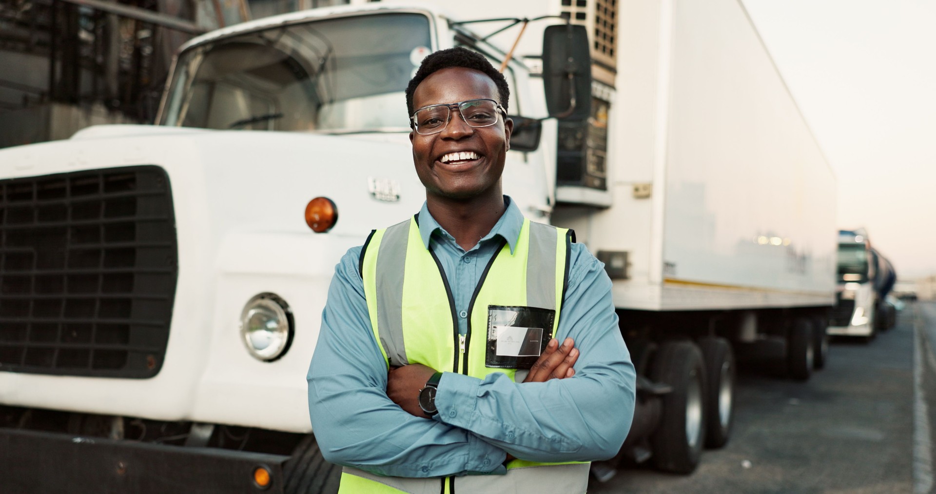 Man, portrait and outdoor at warehouse with confidence for logistics, gear for safety and smile for health. Male driver, happy and outside factory with semi truck for supply chain, job with transport